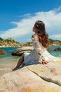 Vertical shot of a pretty Asian girl sitting on rocks near the beach Royalty Free Stock Photo