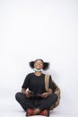 Vertical shot of a pretty young African girl sitting cross-legged with a mask on her jaw Royalty Free Stock Photo