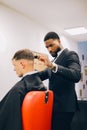 Vertical shot of a professional barber in a suit adjusting a haircut on his customer