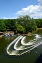 Vertical shot of Pulteney weir of River Avon and people riding a ship under the clouds of the sky