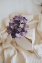 Vertical shot of purple artificial flowers between the pages of a semi-closed white notebook