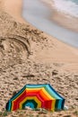 Vertical shot of rainbow colored beach umbrella buried in the sand Royalty Free Stock Photo