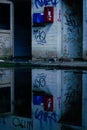 Vertical shot of random graffiti on rusty tiled wall reflecting on water surface