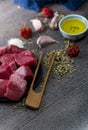 Vertical shot of raw cut meat, garlic cloves, dried pepper, oil on the table - making dinner