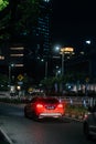 Vertical shot of a red car driving at the road in SCBD area financial district of Jakarta at night