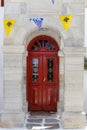 Vertical shot of a red door of a building with a line of national symbol flags hanging in Mykonos Royalty Free Stock Photo