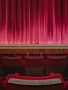 Vertical shot of red empty theatre seats in front of the stage Royalty Free Stock Photo