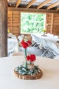 Vertical shot of red flowers in glass jars on a round table in a wedding venue Royalty Free Stock Photo