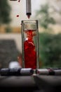 Vertical shot of red ink being poured with a syringe into a glass of water Royalty Free Stock Photo