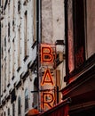 Vertical shot of a red neon BAR sign on the top of a building on a street of a city Royalty Free Stock Photo