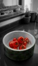 Vertical shot of red ripe tomatoes in a bowl on a grayscaled background