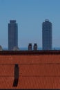 Vertical shot of a red roof in the background of two skyscrapers in the evening