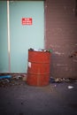 Vertical shot of a red trash bin in front of a fire door with a warning message