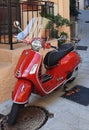 Vertical shot of a red Vespa parked in the streets of Saint Paul in Oise, France