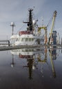 Vertical shot of the reflection of a sailing boat on the water on the pier Royalty Free Stock Photo