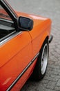 Vertical shot of the right mirror of an orange classic retro BMW 320 car Royalty Free Stock Photo