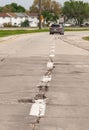 Vertical shot of a road with harmed asphalt coat and a car in the far, Manitoba, Canada Royalty Free Stock Photo