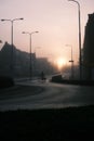 Vertical shot of a road at sunset and a cycler silhouette with a misty houses and sky background Royalty Free Stock Photo