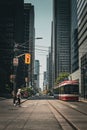 Vertical shot of road train tracks in downtown Toronto with a lady passing from traffic lights