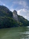 Vertical shot of Rock Sculpture of Decebalus on a green hill against a river in Romania Royalty Free Stock Photo