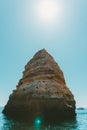 Vertical shot of a rocky cliff in the sea under the bright sky Royalty Free Stock Photo