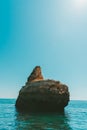 Vertical shot of a rocky cliff in the sea under the bright sky Royalty Free Stock Photo