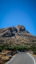 Vertical shot of rocky mountains with a curving road in Keratokampos, Crete Royalty Free Stock Photo