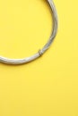 Vertical shot of roll of metal wire isolated on a yellow background