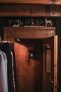 Vertical shot of a room with clothes a wooden door with deer statues and a black hanging phone