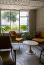 Vertical shot of a room with yellow armchairs, a table in the center, and plants.