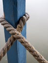 Vertical shot of a rope tied around a blue wooden column