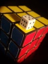 Vertical shot of Rubik's cube and white dice on top isolated on a black background