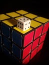 Vertical shot of Rubik's cube and white dice on top isolated on a black background Royalty Free Stock Photo