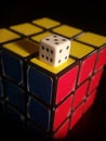 Vertical shot of Rubik's cube and white dice on top isolated on a black background Royalty Free Stock Photo