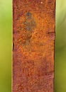 Vertical shot of a rusty iron piece with a green background