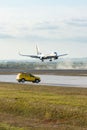 Vertical shot of a Ryanair plane landing in Vatry airport, yellow car parked near