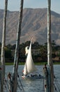 Vertical shot of a sailboat leaving the pier, beautiful mountains in the background