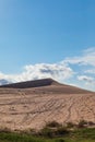 Vertical shot of sand dune under cloudy blue sky Royalty Free Stock Photo