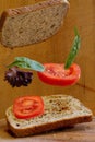 Vertical shot of sandwich bread slices, tomato slices and lettuce on wooden background