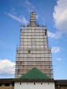 Scaffolding from planks around old bell tower. Background blue sky with clouds. Royalty Free Stock Photo