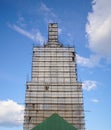 Scaffolding from planks around old bell tower. Background blue sky with clouds. Royalty Free Stock Photo