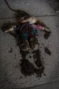 Vertical shot of a scary dirty stuffed doll on the ground