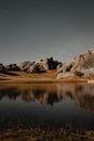 Vertical shot of a scenic lakeside with a reflection of rocky formations against the blue sky