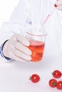 Vertical shot of a scientist adding toxic substances to cherry tomatoes in a laboratory