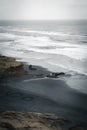 Vertical shot of the sea and a black-sand beach on a cloudy day Royalty Free Stock Photo