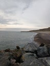 Vertical shot of the sea with huge rocks on the shore on a cloudy day Royalty Free Stock Photo