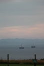 Vertical shot of the sea surrounded by cable car, mountains, blue sky and field Royalty Free Stock Photo