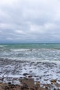 Vertical shot of the sea waves reaching the seashore on a cloudy day Royalty Free Stock Photo