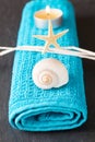 Vertical shot of a seashell, a seastar and a lit tea candle on a blue towel