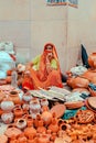 Vertical shot of a senior female in a red cloth selling clay pots in the streets of Jaipur, India